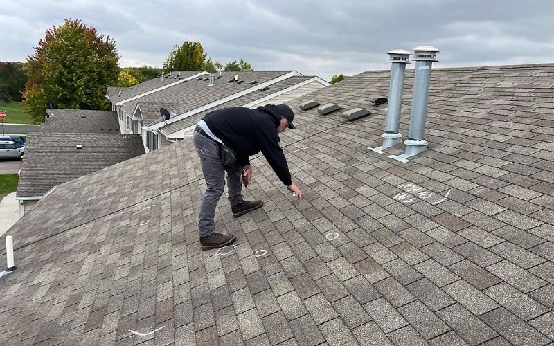 Roofing consultant marking damage on roof with chalk