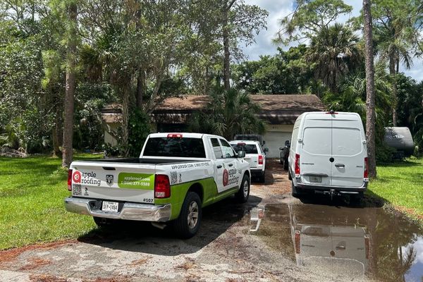 Apple Roofing truck parked next to other vehicles in a Florida home's driveway