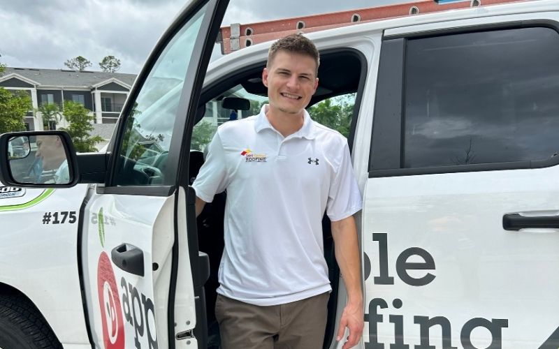 Roofing consultant in stepping out of an Apple Roofing work truck